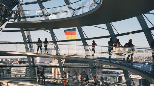 Reichstagskuppel Berlin mit Deutschlandfahne und Besuchern